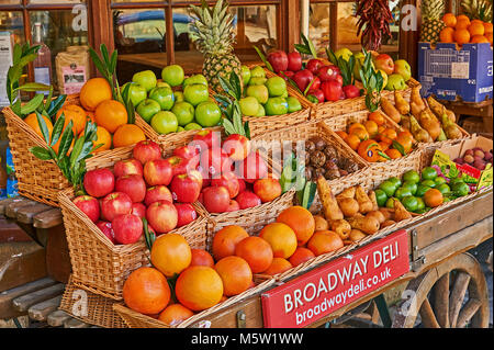 In vecchio stile frutta e verdura barrow visualizzando una vasta scelta di frutta fresca e verdura fuori del locale deli store in Broadway, Worcestershire Foto Stock