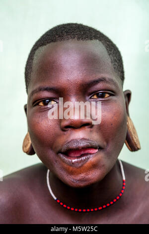 Un ritratto di una giovane donna dalla tribù dei Mursi, villaggio dei Mursi, Valle dell'Omo, Etiopia Foto Stock