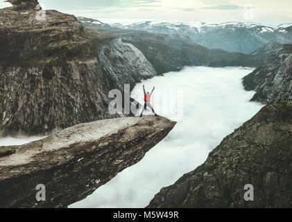 Uomo di saltare sul Trolltunga scogliera rocciosa edge in Norvegia montagne Viaggi avventura dello stile di vita felice concetto emozionale estrema viaggio vacanze outdoor ab Foto Stock