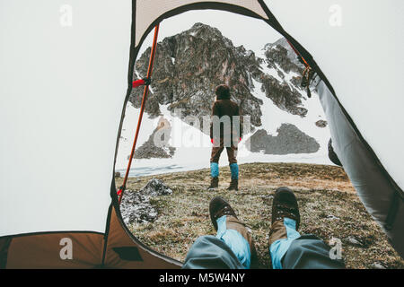 Camping viaggiare giovane vista dalla tenda ingresso donna a camminare in montagna uomo piedi rilassante all'interno del concetto di stile di vita Vacanze avventura all'aperto Foto Stock