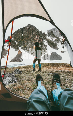 Lo stile di vita di viaggio camping giovane vista dalla tenda ingresso donna a camminare in montagna uomo piedi rilassante all'interno di avventura vacanze outdoor Foto Stock