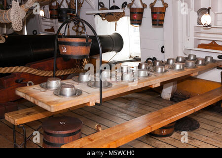 Di marinai di cui pasticcio tabella ( rievocazione storica ) tra il cannone / pistole sulla pistola mazzo di HMS Warrior. Portsmouth Historic Dockyard. Regno Unito. (95) Foto Stock