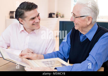 Senior Uomo che guarda un Album di Foto Con figlio adulto Foto Stock