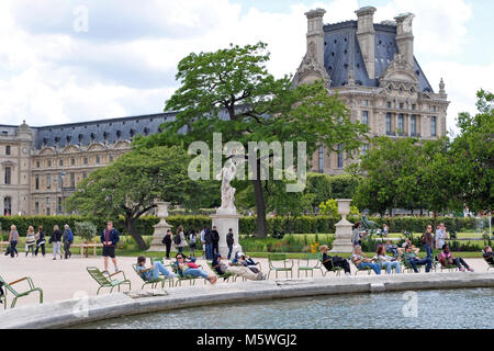 Parigi, Francia, 22 Giugno: parigini e gli ospiti della città sono in appoggio nei pressi di un laghetto nel parco delle Tuileries sullo sfondo del Louvre in un bri Foto Stock