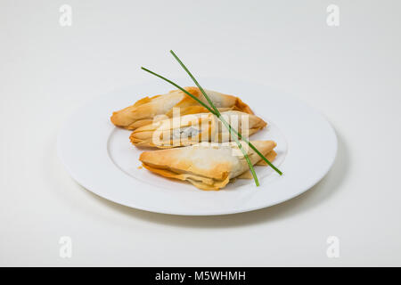 Samosa su una piastra bianca su sfondo bianco Foto Stock