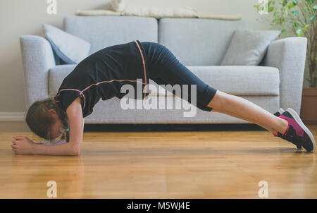 Bambina facendo esercizi per il sistema ABS a casa. Plank. Foto Stock