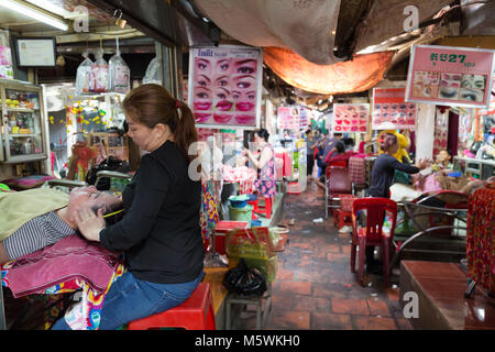 Street terapista di bellezza facendo un trattamento viso per un cliente, un esempio di stile di vita in Cambogia; Phnom Penh in Cambogia, in Asia Foto Stock