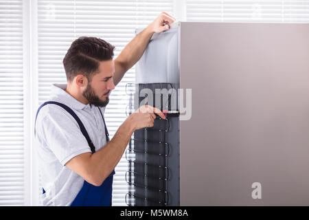 Foto di maschio fissaggio tecnico frigorifero in cucina Foto Stock