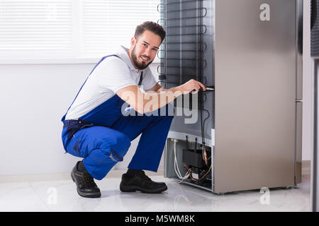 Foto di maschio fissaggio tecnico frigorifero in cucina Foto Stock