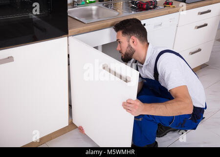 Giovani tuttofare di fissaggio porta lavello in cucina Foto Stock