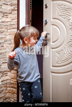 Una bambina in appartamento e chiude la porta. Foto Stock