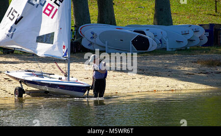 Maschio e femmina tenendo dinghy in barca a vela in acqua Foto Stock