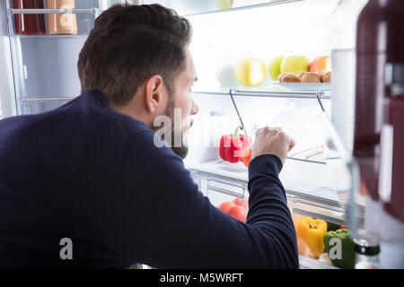 Close-up di un giovane uomo di rimozione di acqua in bottiglia dal frigorifero Foto Stock