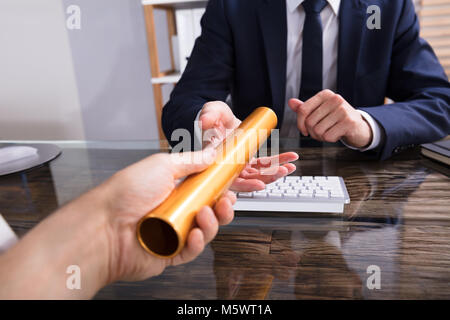 Close-up di mano di una persona che passa il relè d'oro testimone a commercianti Foto Stock