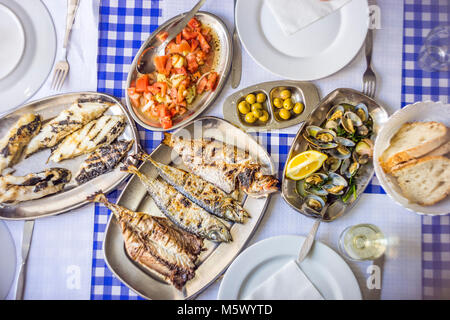 Festa del pesce: spigola, Golden, suro accompagnato con insalata di pomodoro, vongole, pane e vino bianco, Portogallo Foto Stock