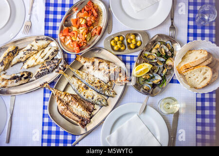 Festa del pesce: spigola, Golden, suro accompagnato con insalata di pomodoro, vongole, pane e vino bianco, Portogallo Foto Stock