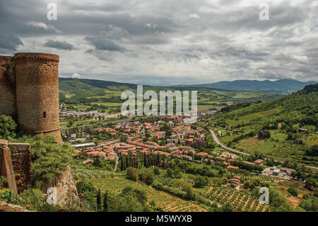 Torre in pietra, verdi colline, vigneti e sui tetti della città vicino a una strada. Dalla città di Orvieto, un antico, piacevole e ben conservato borgo medievale. Foto Stock