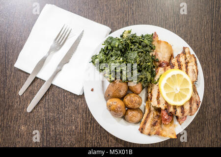 Misto di carne con spinaci e patate servita su piastra bianca Foto Stock