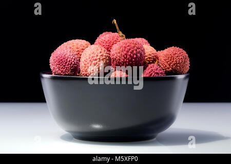Il lychee frutti in un recipiente isolato su sfondo scuro Foto Stock