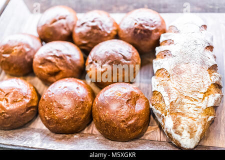 Primo piano della fresca bruna rigata di pasta acida cotta pagnotte di pane in panetteria con molti panini rotoli Foto Stock