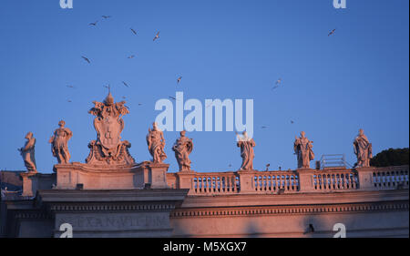 La Basilica di San Pietro Saint statue sul colonnati durante il tramonto Foto Stock