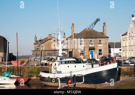 Barche in basso bacino d'acqua e casa con una gru Dietro il tetto della casa in zona industriale banchina a Glasson Dock Lancashire Foto Stock