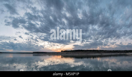 Ampio Panorama di nuvole temporalesche riflettendo sul grande lago al tramonto Foto Stock