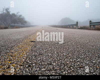 Basso angolo vista della strada che conduce alla fitta nebbia Foto Stock