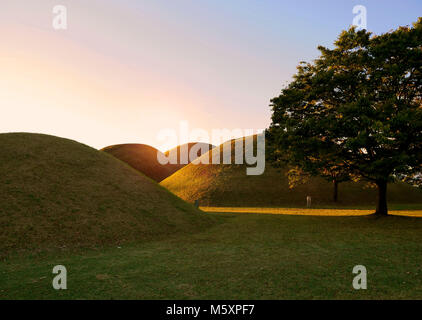 Il sorgere del sole sopra i Tumuli park royal tombe complesso situato in Gyeongju, Corea del Sud. Foto Stock