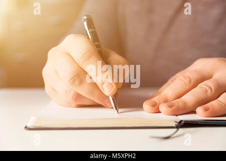 Voce maschile la scrittura a mano in notebook con penna Foto Stock