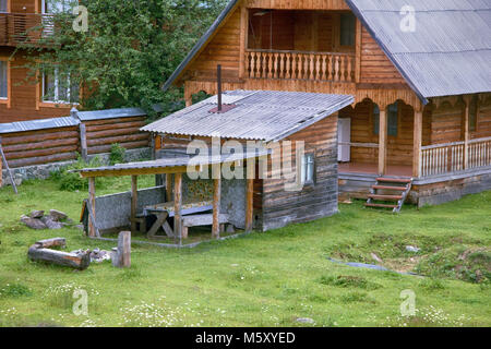 Casa di villaggio russo famiglia singola. Casa con architravi scolpiti e veranda. piccola cucina estiva per la cottura nella stagione calda. Altai. Foto Stock