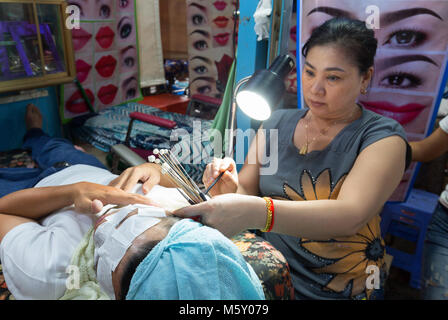 Street terapista di bellezza facendo un trattamento viso per un cliente, esempio di cultura in Cambogia; Phnom Penh in Cambogia, in Asia Foto Stock