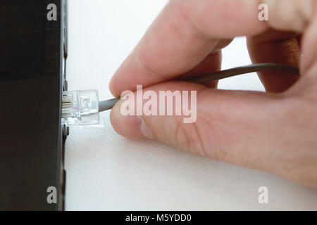 Mano umana collegando una LAN cordicelle nel personal computer laptop, il fuoco selettivo Foto Stock