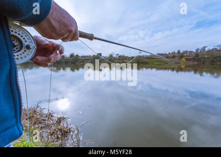 Un pescatore di trote godendo di una serata su di un lago calmo. Foto Stock