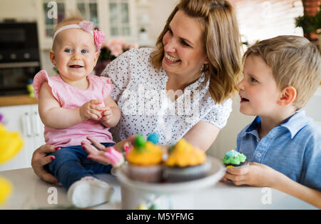 Dei bambini felici con la madre di mangiare i tortini Foto Stock