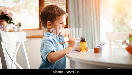 Carino piccolo ragazzo di pittura delle uova di pasqua Foto Stock