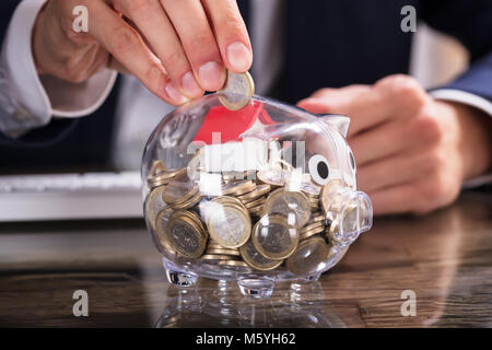 Close-up di un imprenditore di mano inserire monete In Piggybank Foto Stock