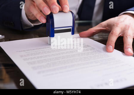 Close-up di un imprenditore la mano di Timbratura di documenti Office Foto Stock