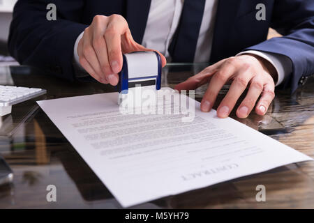 Close-up di un imprenditore la mano di Timbratura di documenti Office Foto Stock