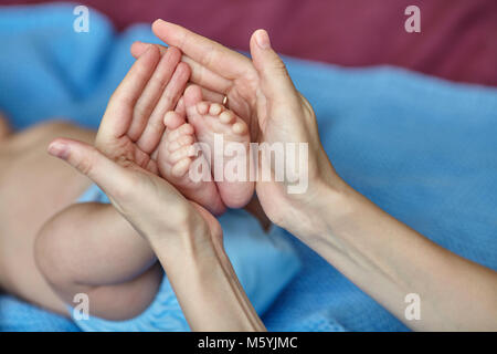 Madre le mani dell azienda con cura del bambino in piedi con amore, il fuoco selettivo, primo piano Foto Stock