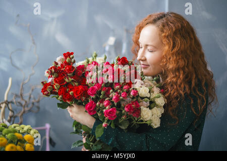 Ragazza con rose faccia chiudendo gli occhi e gustano il profumo delle rose Foto Stock