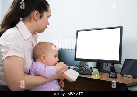 Donna con il suo bambino per mezzo di computer con schermata bianca vuota Foto Stock