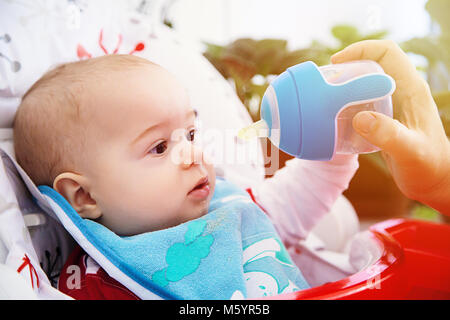 Adorabili curioso bimbo beve acqua dalla bottiglia. Felice ed emozionato. Foto Stock