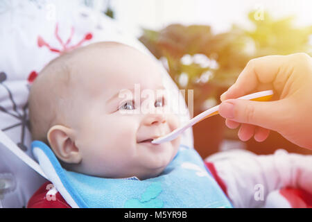 Funny baby hanno il pranzo con il cucchiaio a tavola. Foto Stock