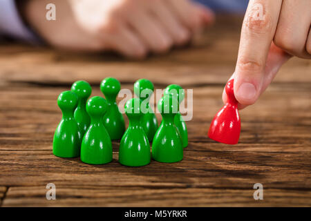 La mano di una persona Picking rosso figura sulla scrivania in legno Foto Stock
