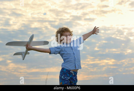 Little Boy tenendo un aeroplano in legno modello sul campo Foto Stock