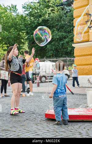 Bambini che giocano con le bolle più grandi a Olha Kobylianska Street zona pedonale in Chernivtsi, Bukovina Regione, Ucraina Foto Stock