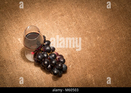 Vino rosso in un bicchiere con mosti di uve Foto Stock