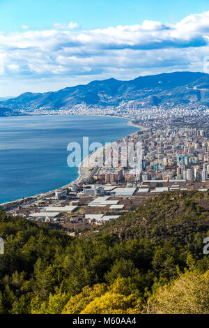 Birds Eye view shot mediterraneo della città costiera di Alanya in Turchia con collina coperta da una foresta al primo piano e Alanya di aree per lo sviluppo di un Foto Stock