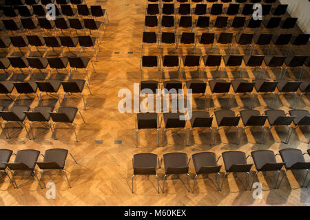 Sedie in fila su di un pavimento in legno, per un concerto, una performance, o una conferenza. Foto Stock